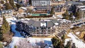 Ein mehrstöckiges Hotel mit Balkonen, einem Parkplatz und verschneiter Umgebung.