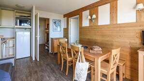 Eine kompakte Küche mit Mikrowelle, Kühlschrank und einem Holzespeisetisch mit Stühlen.