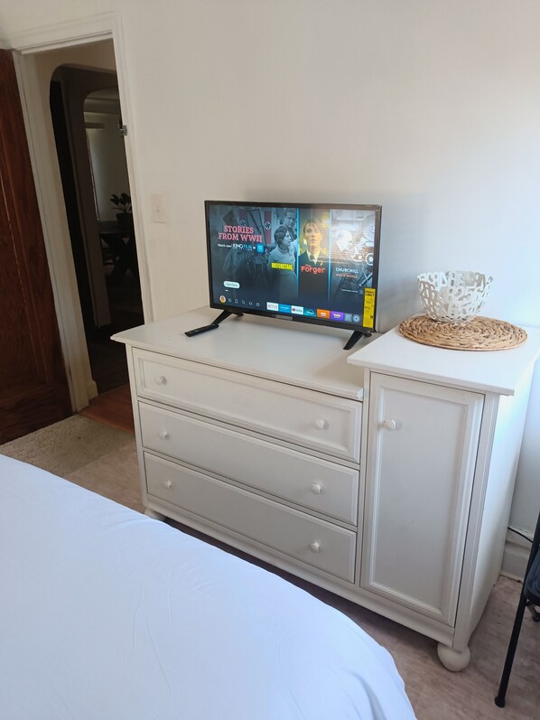 A white dresser with a flat-screen TV displaying a movie selection.