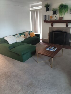 Una sala de estar con un sofá verde, una mesa de centro de madera y una chimenea.