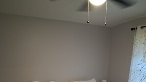 Un dormitorio con cama, mesitas de noche y ventilador de techo.