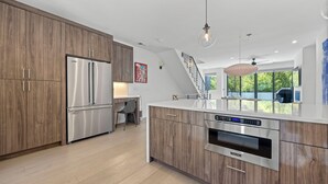 Eine moderne Küche mit Edelstahlgeräten, Holzschränken und einem Essbereich mit Aussicht.