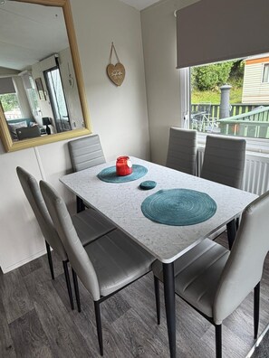 A dining area with a table, chairs, and a mirror. - Family & Dog Friendly 2-Bed Caravan, Sleeps 6 (Newton Stewart)