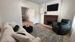 Ein Wohnzimmer mit einer Couch, Hocker und Kamin.
