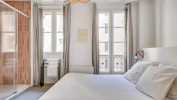 Une chambre d’hôtel avec un grand lit, un espace douche et un balcon avec vue.