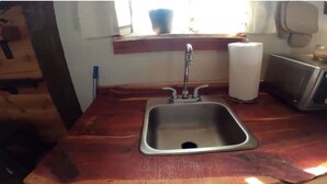 Une cuisine dotée d’un évier en acier inoxydable, d’un plan de travail en bois et d’une fenêtre offrant une vue agréable.