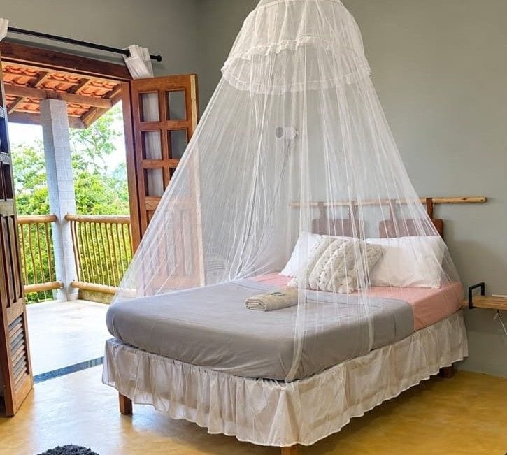 A bed with a white canopy, a wooden headboard, and a balcony with a wooden railing.