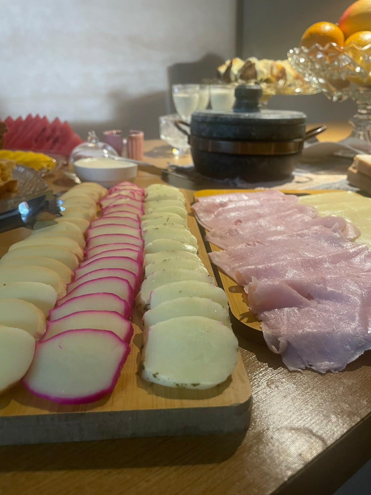 Un tagliere con fette di ravanelli e prosciutto.
