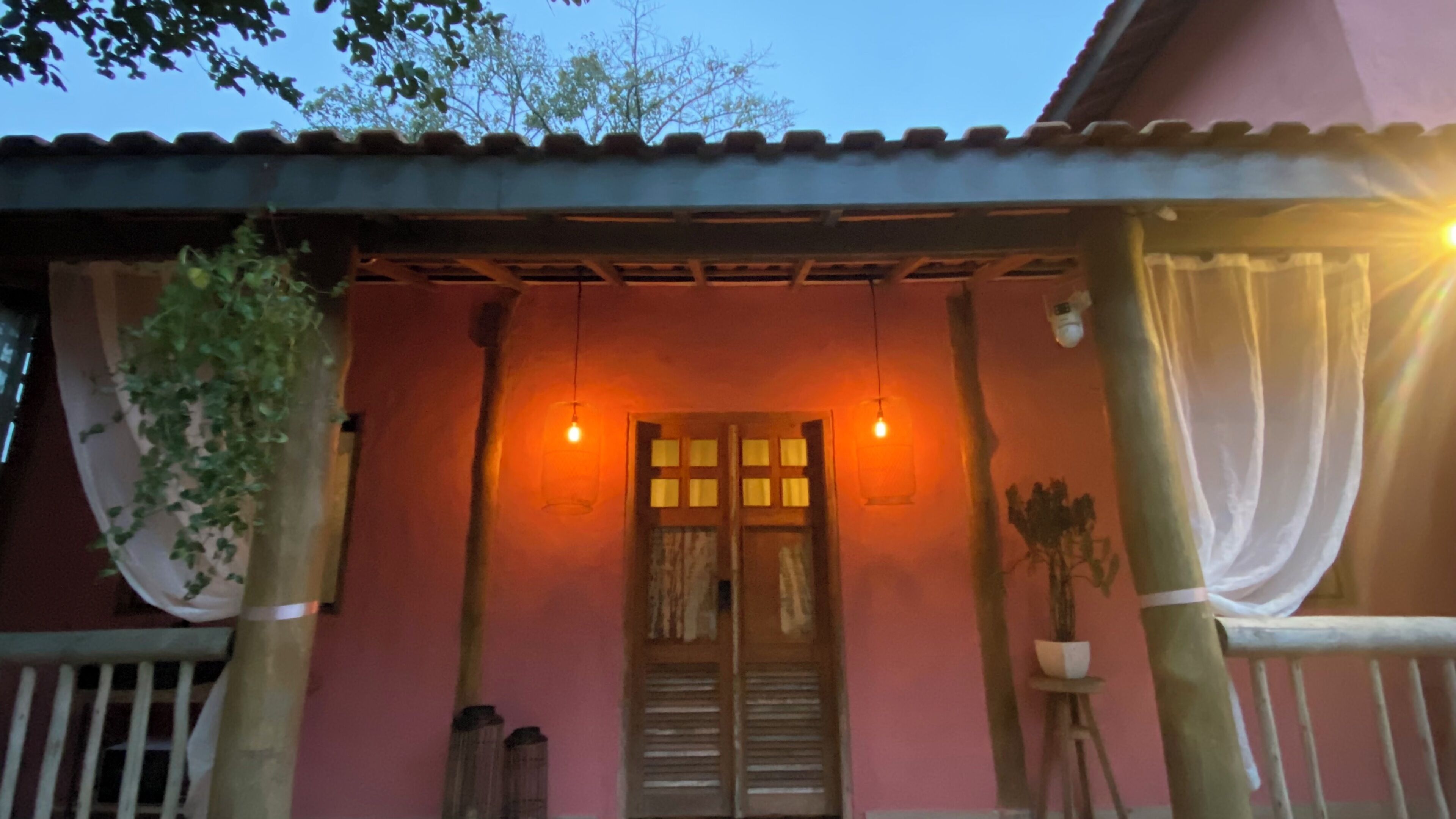 A building with a pink facade, a wooden door, and two hanging light fixtures.