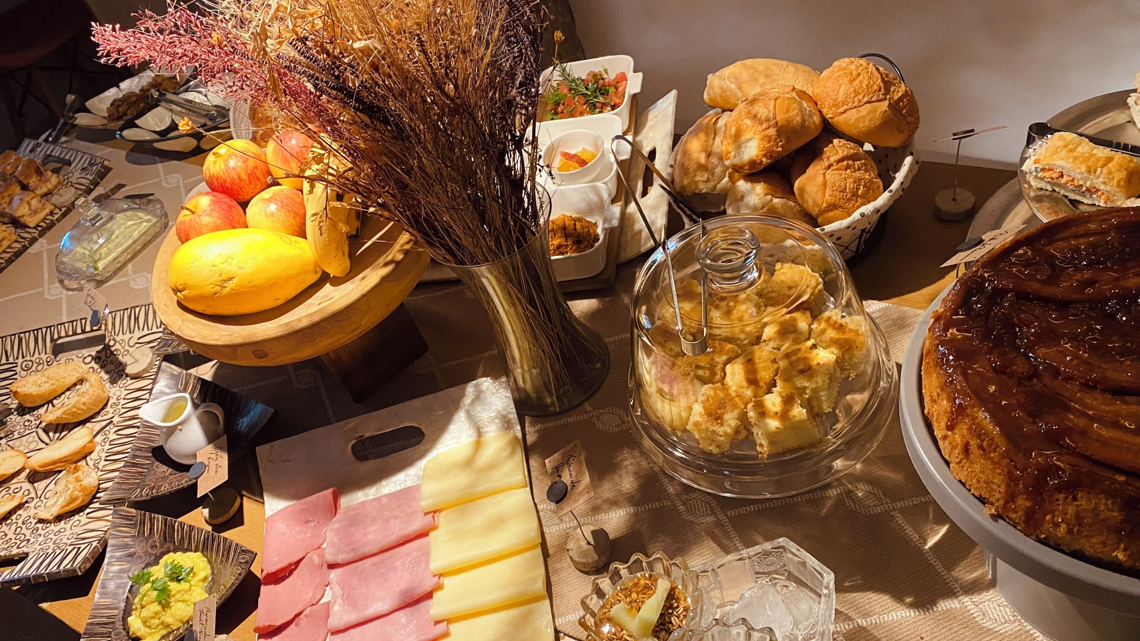 A buffet table with various food items including fruits, cheeses, and pastries.