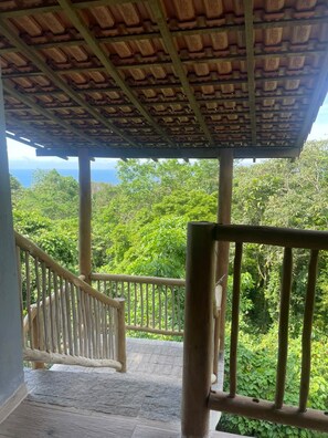 A wooden staircase leading to a covered area with a view of lush greenery. - Pousada Refúgio da Ilha (Ilhabela)