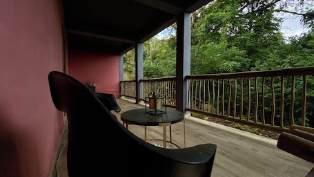 A covered outdoor seating area with a table and chairs, a railing, and a view of dense greenery.. Pousada Refúgio da Ilha