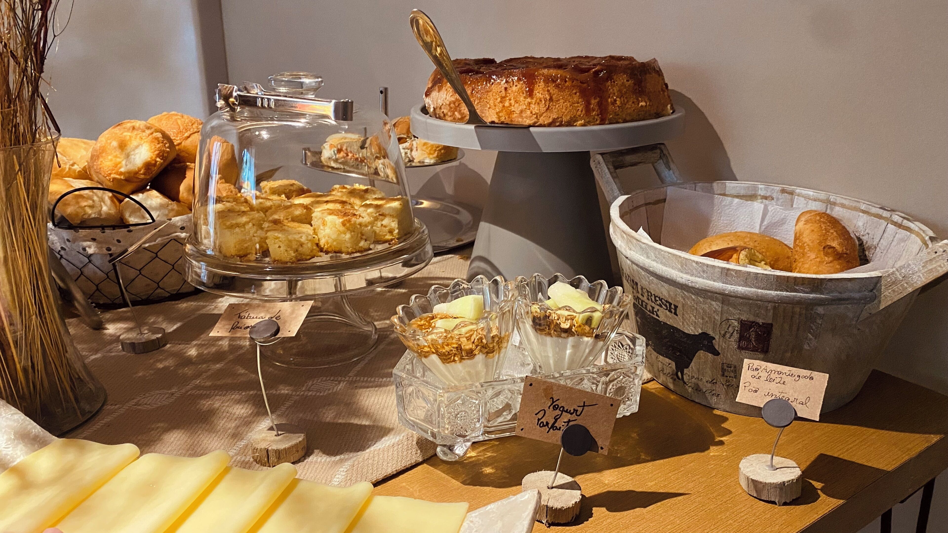A buffet with various food items including pastries, bread, and cheese.