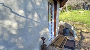 Ein Haus mit einer Veranda, einem hängenden Blumentopf und einem kleinen Garten.