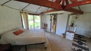 Ein Schlafzimmer mit Bett, Schreibtisch, Stuhl, Fenster und Blick ins Freie.