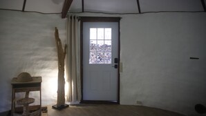 Ein Zimmer mit einer weißen Tür, einer Holzkratzbaum und einem Fenster mit Blick auf Bäume.