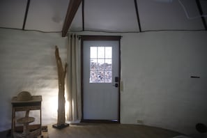 Une pièce avec une porte blanche, un arbre à chat en bois et une fenêtre donnant sur des arbres.