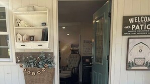 Puerta de madera que da a una habitación con una silla y un felpudo.