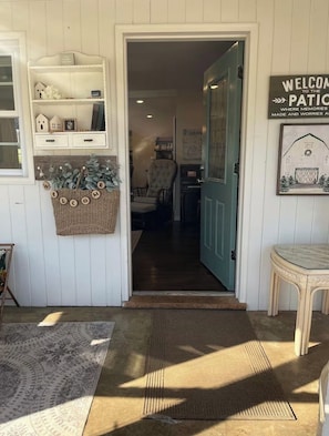 A wooden door leading to a room with a chair and a welcome mat.