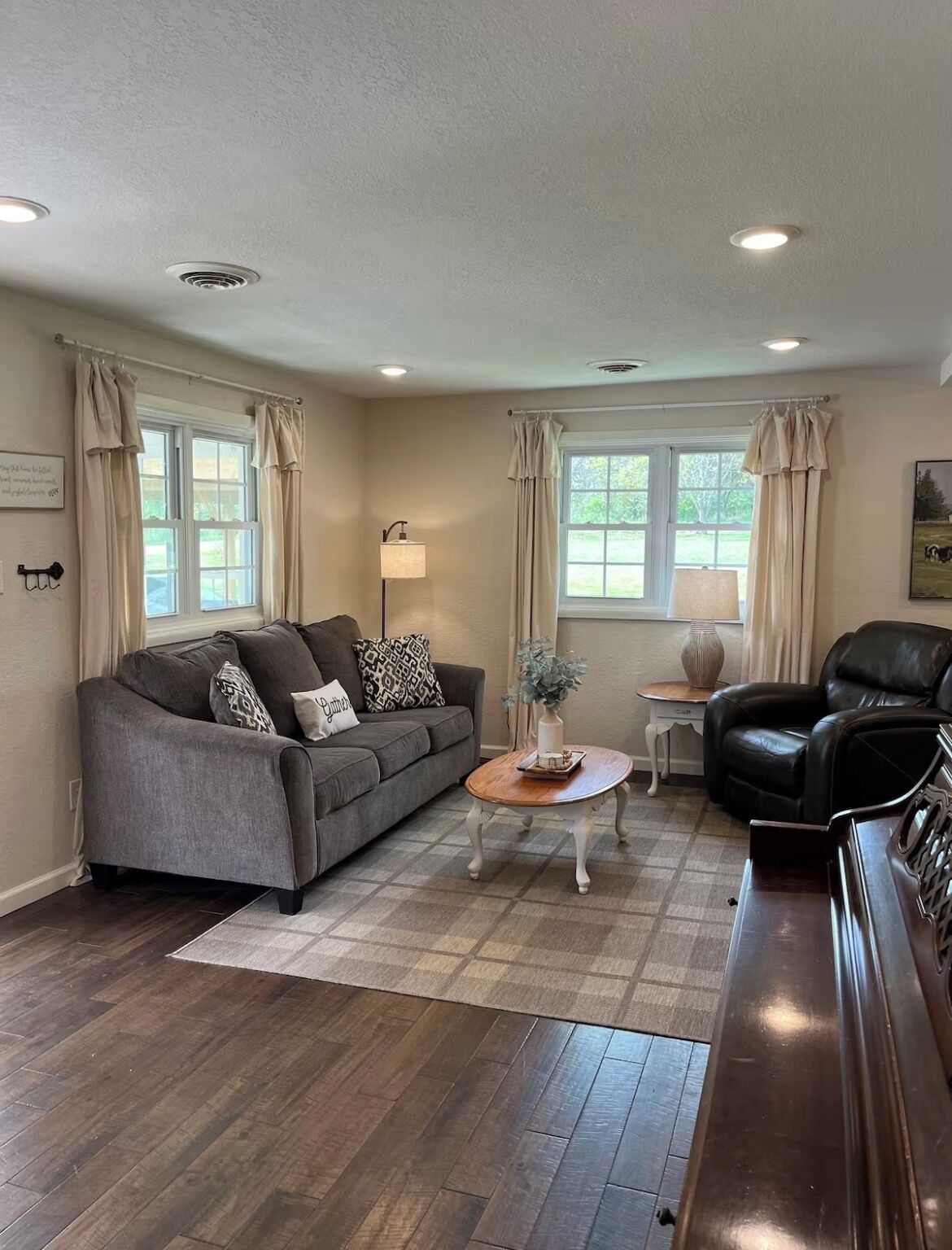 A living room with a sofa, a coffee table, a chair, and a piano.