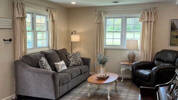 A living room with a sofa, a coffee table, a chair, and a piano.