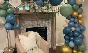 A room with a fireplace, a sofa, and a wall decorated with balloons.