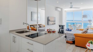 Een moderne keuken met een centraal eiland, een eethoek met uitzicht, en een slaapkamer met een bed en raam.
