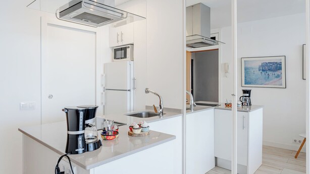 Een moderne keuken met een magnetron, koelkast en koffiezetapparaat.