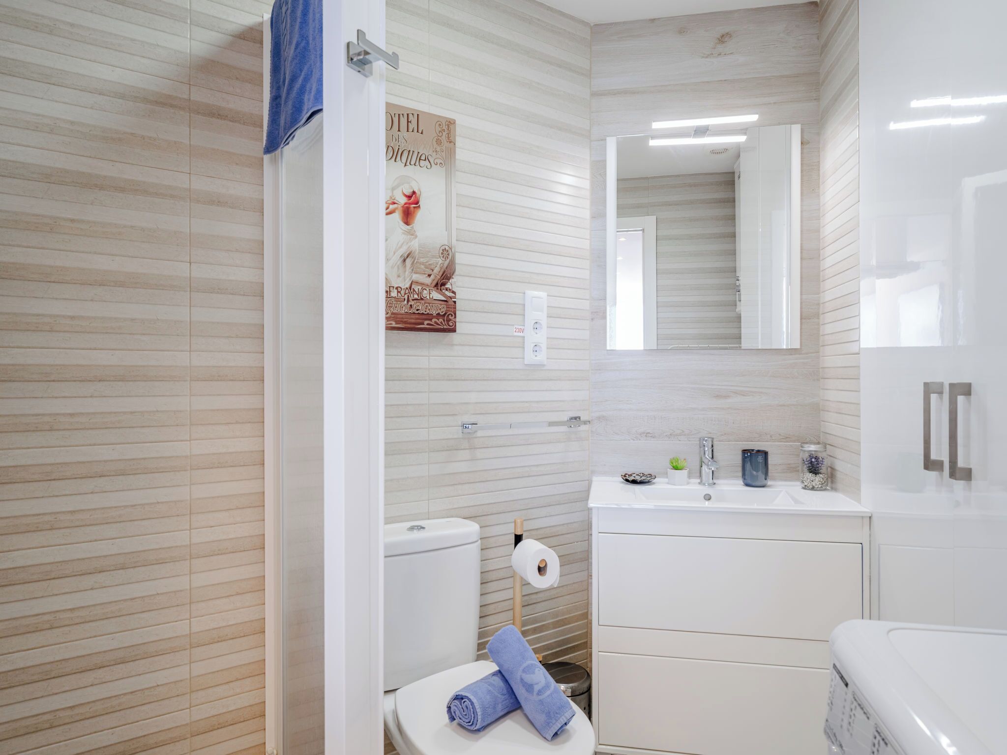 A bathroom with a toilet, sink, mirror, and towel rack.