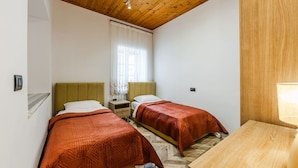 A room with two beds, wooden ceiling, white walls, and a small table with a lamp. - Konak Olive Guesthouse Heart of Vlora (Vlorë)