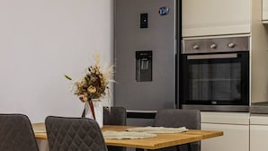 A modern kitchen with a built-in refrigerator, oven, and a dining area with a table and chairs. - Konak Olive Guesthouse Heart of Vlora (Vlorë)