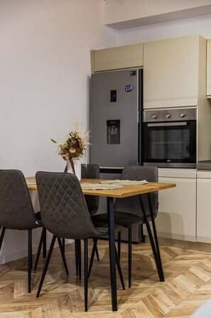 Eine moderne Küche mit Einbaukühlschrank, Backofen und einem Essbereich mit Tisch und Stühlen.