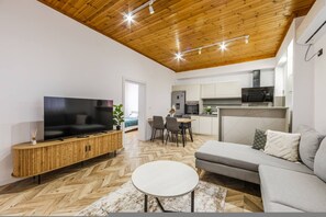 Een moderne woonkamer met een televisie, bank en visgraatvloer.