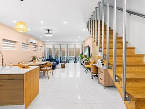 Ein modernes Interieur mit Kücheninsel, Essbereich und Treppe mit Holzhinweisstufen und Metallgeländern.