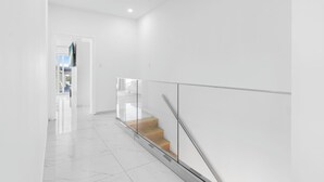 A modern interior with a glass railing, a staircase, and a clean, white color scheme. - The Luxe A5 | Beachside @ The Drake Residences (Simpson Bay)