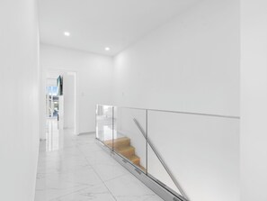 Un interior moderno con barandilla de vidrio, una escalera y una paleta de colores limpia en blanco.