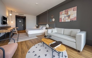 Una habitación de hotel moderna con una cama, un sofá, un escritorio y un televisor.