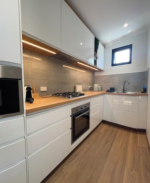 A modern kitchen with white cabinetry, a built-in oven, a gas stove, and a window above the sink. - il Villinno;  Luxury Villa in Mosman Park (Mosman Park)