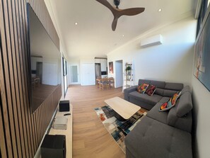 A modern living room with a grey sofa, a flat-screen TV, a ceiling fan, and a wooden floor. - il Villinno;  Luxury Villa in Mosman Park (Mosman Park)