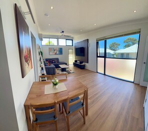 A spacious living area with a dining table, chairs, a sofa, and a TV mounted on the wall. - il Villinno;  Luxury Villa in Mosman Park (Mosman Park)