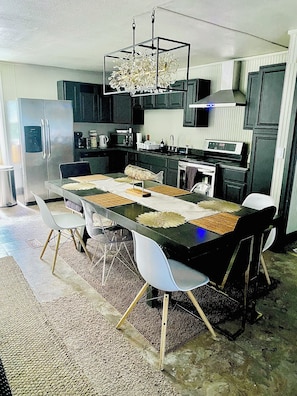 A modern kitchen with a dining table, chairs, and a chandelier.
