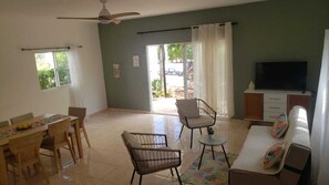 A living room with a dining table, chairs, a sofa, a TV, and a ceiling fan. - Yellow House Río San Juan, Oasis Tropical Pool (Rio San Juan)