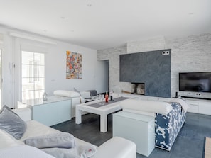 A modern living room with a fireplace, white furniture, and a large TV. - Medussa by Interhome (Dénia)