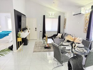 Ein modernes Wohnzimmer mit einer Couch, einem Glastisch und einem Essbereich mit Stühlen.