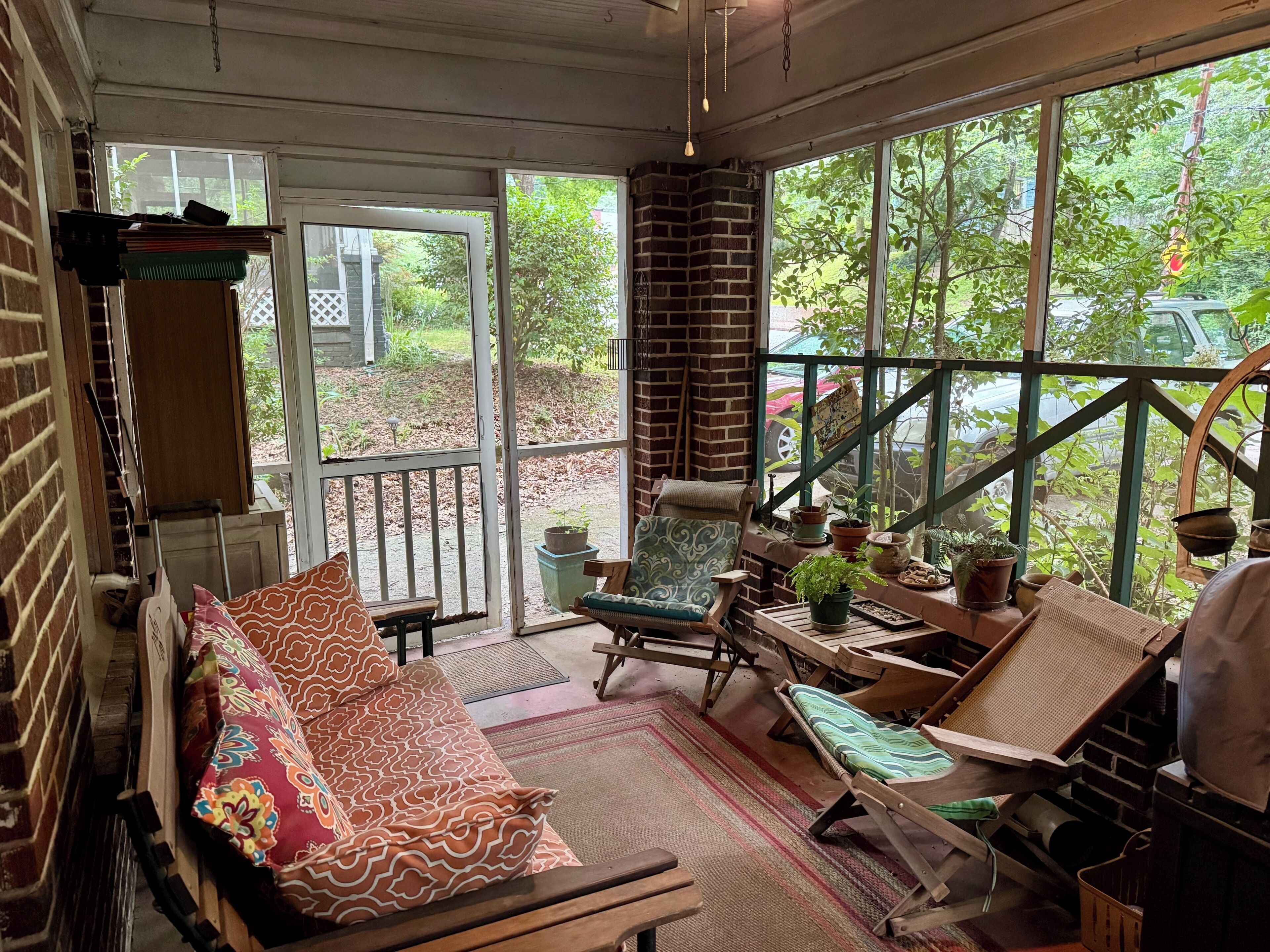 A cozy room with a sofa, chairs, a table, and a view of greenery outside.