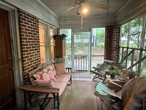 A covered porch with a brick wall, a wooden bench, a table, and a chair. - Cozy 1-bedroom bungalow in East Atlanta (Atlanta)