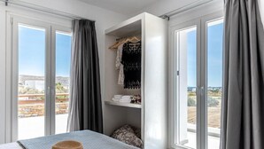Un dormitorio con cama, un sombrero, un armario y vistas al exterior.
