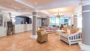 A spacious lobby with a high ceiling, large columns, wicker furniture, and a central seating area. - Stunning 4-person Sea View Haven (Roquebrune-sur-Argens)