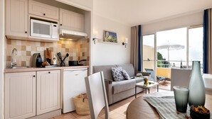 A compact living space with a kitchenette, a sofa, a dining area, and a balcony with a view. - Stunning 4-person Sea View Haven (Roquebrune-sur-Argens)