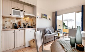 Un espacio habitable compacto con kitchenette, sofá, comedor y balcón con vistas.